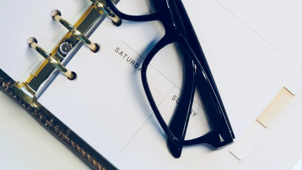 Calendar and notebook on a desk beside a cup of coffee